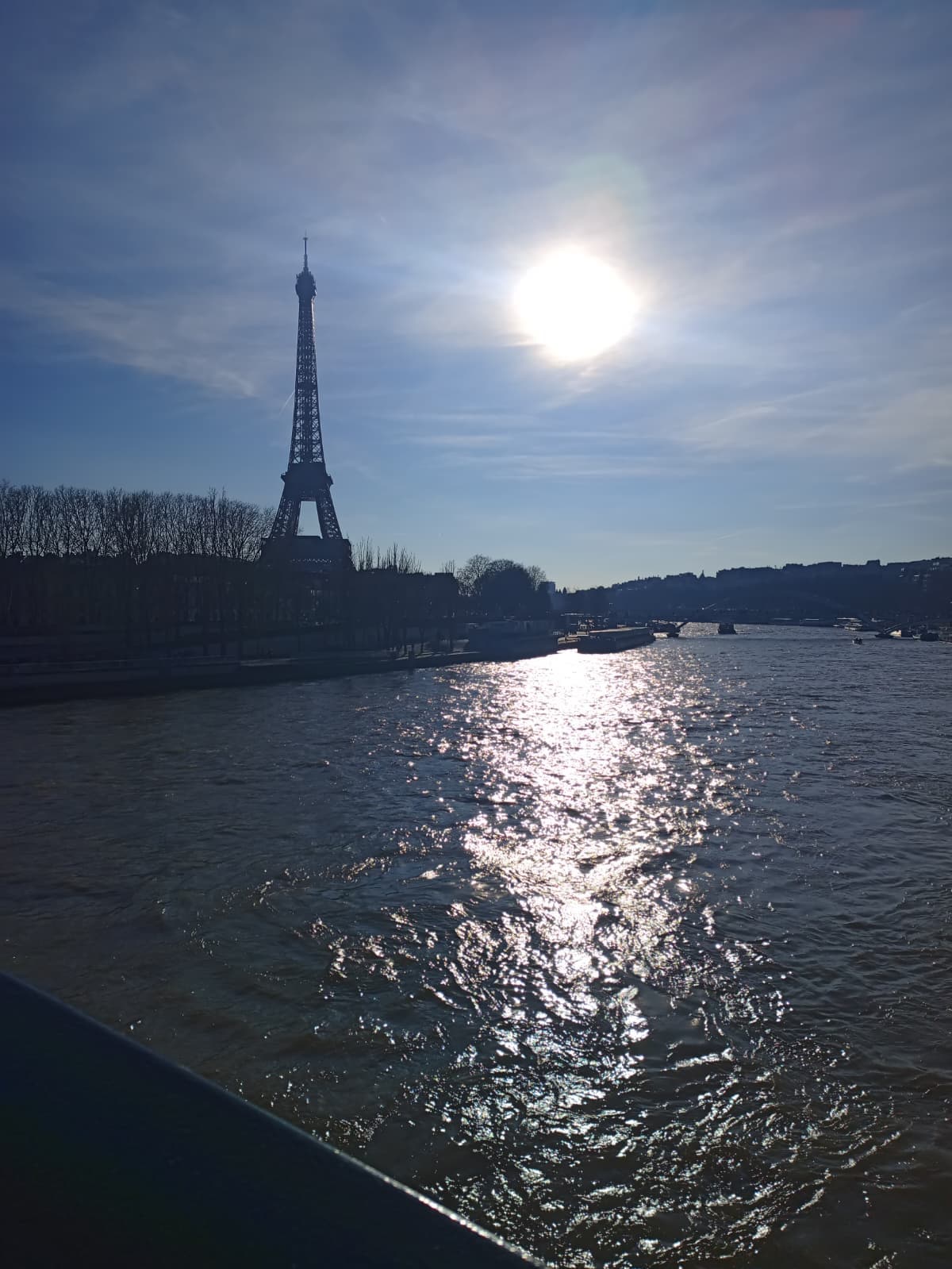 The Eiffel Tower and the sun reflecting over the Seine.