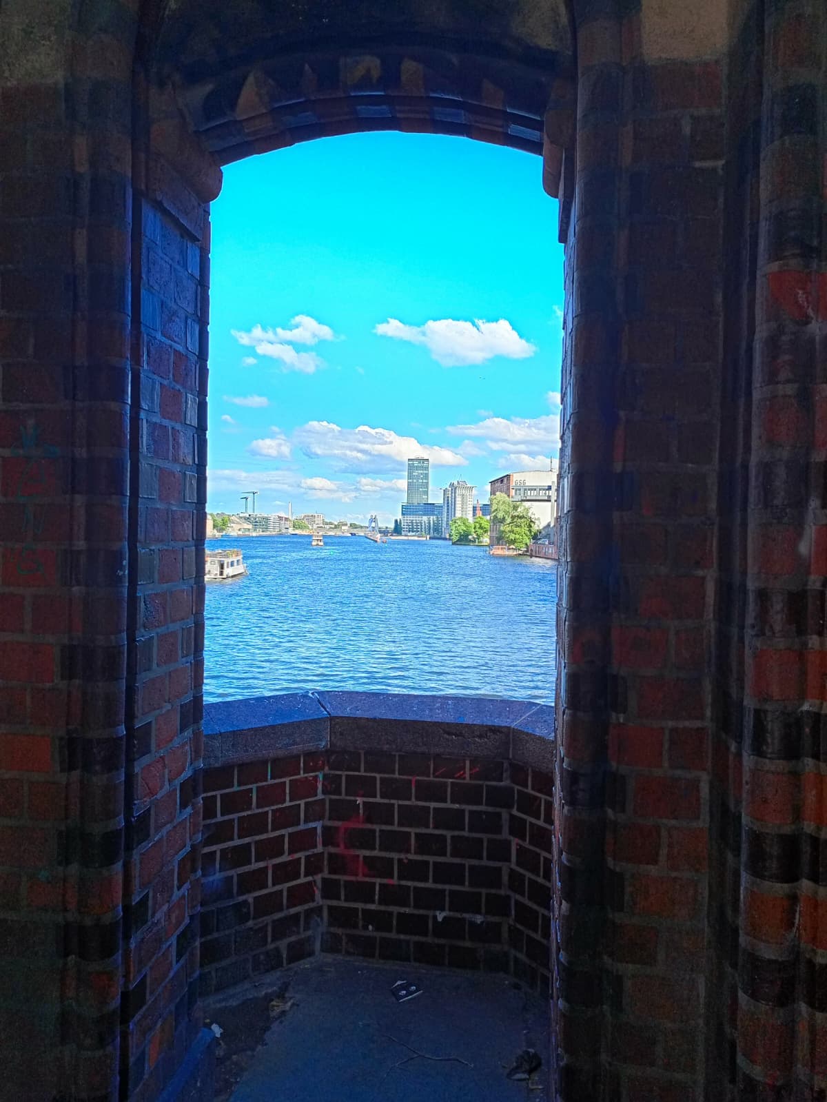 Framed river view through a brick archway in Berlin.