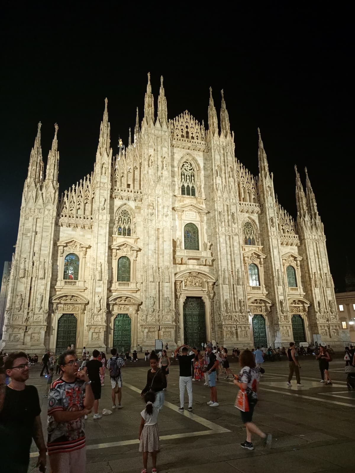 Full view of the illuminated Milan Cathedral at night.