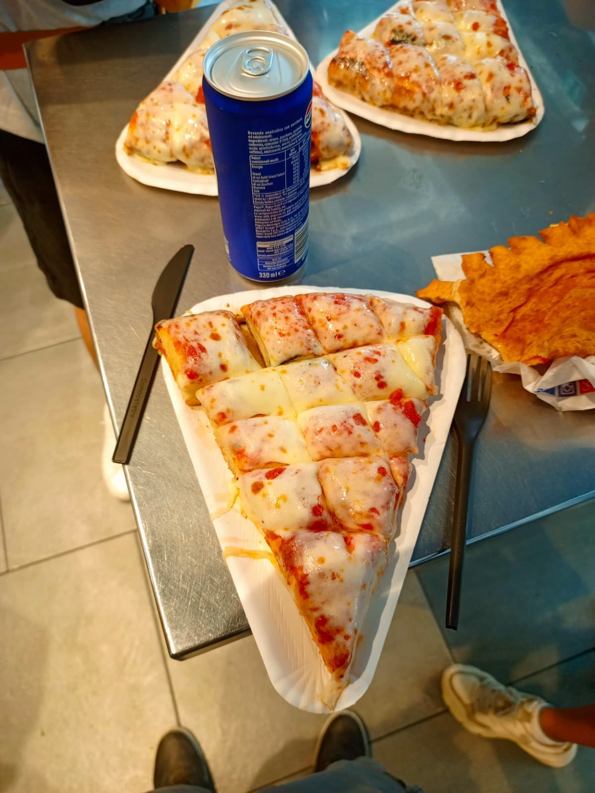 A cheesy slice of pizza served with a can of Pepsi.