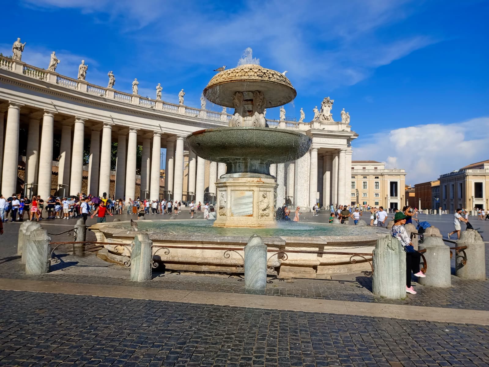 The fountain at St. Peter’s Square with the colonnades embracing the crowd.