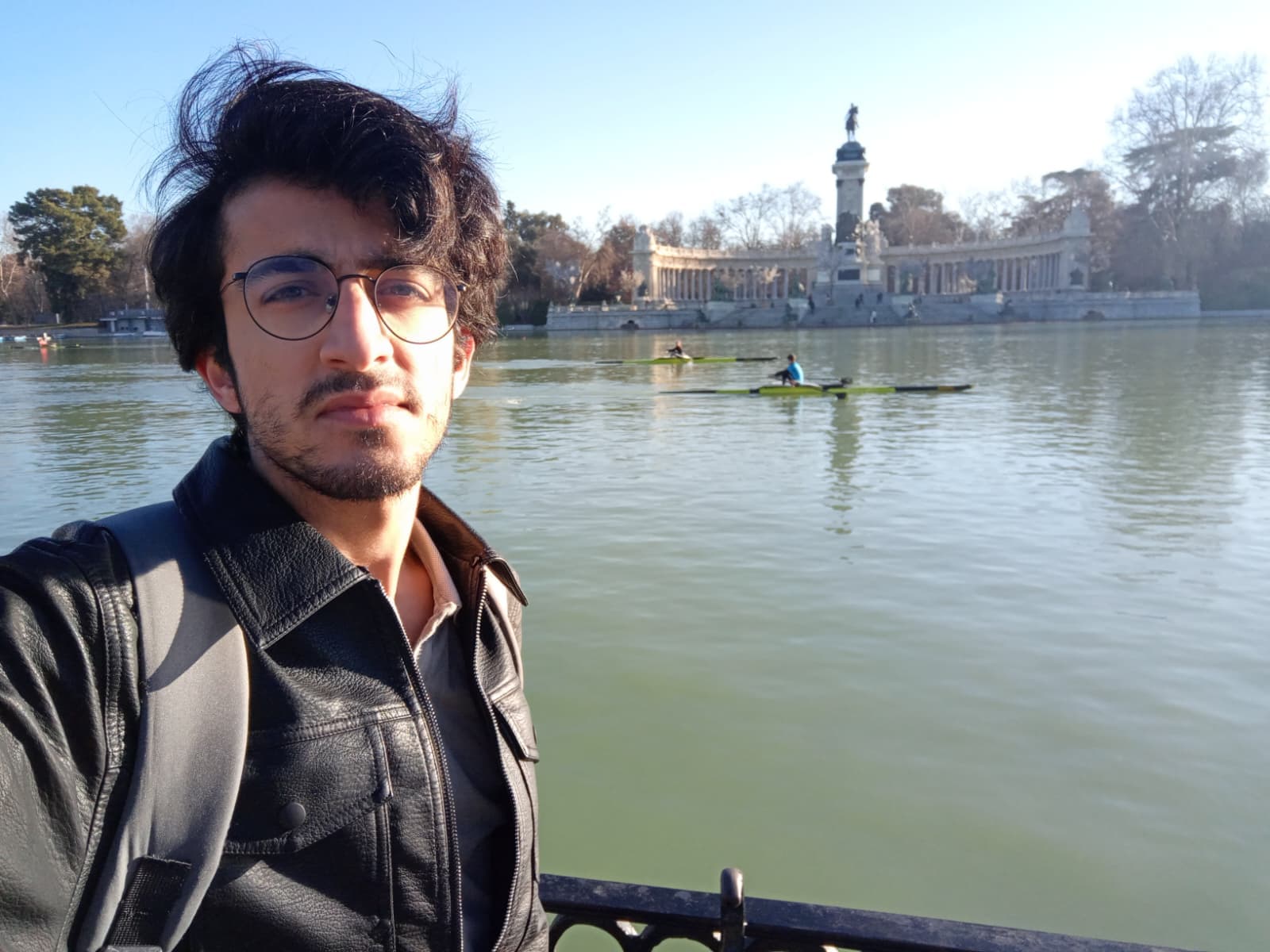 Selfie by the Retiro Park lake with rowers in the background.